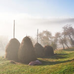 Amazing mountain landscape with fog and a haystack in autumn