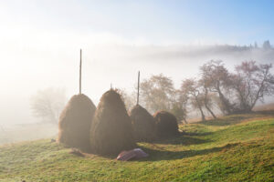 Amazing mountain landscape with fog and a haystack in autumn