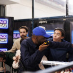 mad angry people shoppers lined up early store entrance attacking security guard breaking into shopping mall black friday sales police officer talking by walkie talkie trying hold crowd